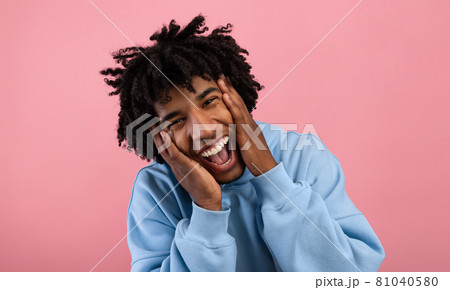 Funky African American teen opening mouth in shock, shouting WOW, holding his face, looking at camera on pink background Funky African American teen opening mouth in shock, shouting WOW, holding his face, looking at camera on pink background 81040580