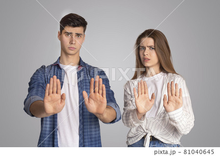 Dissatisfied and upset young man and woman gestures and fenced off with their hands and look at camera Dissatisfied and upset young man and woman gestures and fenced off with their hands and look at camera 81040645