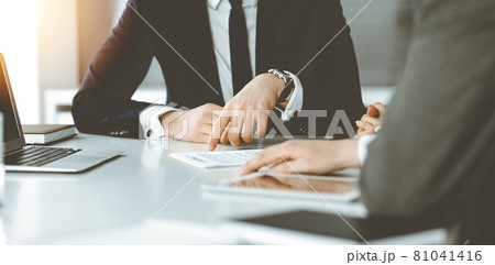Unknown businessmen and woman sitting, using laptop computer and discussing questions at meeting in sunny office, close-up. Success concept 81041416