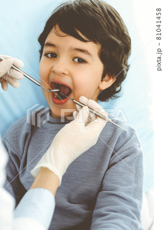 Little arab boy sitting at dental chair with open mouth during oral checking up with dentist doctor. Stomatology concept 81041458