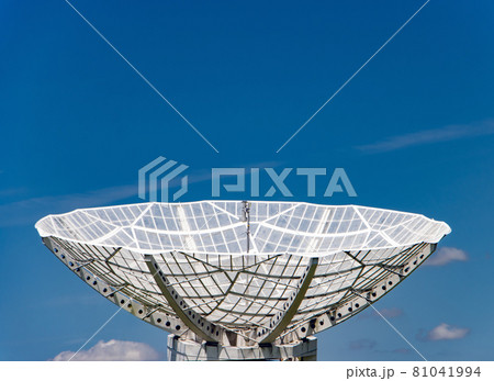 A giant satellite dish for receiving a signal is aimed up to the blue sky. 81041994