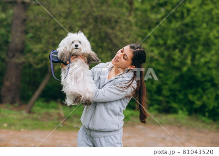 Beautiful woman holding a dog in her arms Beautiful woman holding a dog in her arms 81043520