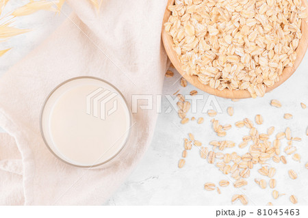 Glass with oat milk and a bowl with oat flake on white stone table, top view Glass with oat milk and a bowl with oat flake on white stone table, top view 81045463