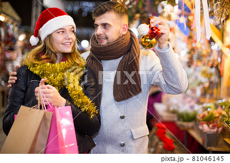 Joyful couple in Christmas hat with Christmas toys at fair Joyful couple in Christmas hat with Christmas toys at fair 81046145