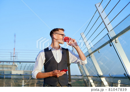 businessman with a smartphone drinks coffee on the office terrace . 81047839