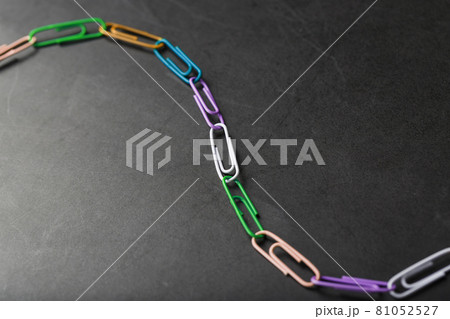 Multi-colored paper clips with a chain on a black background. Multi-colored paper clips with a chain on a black background. 81052527