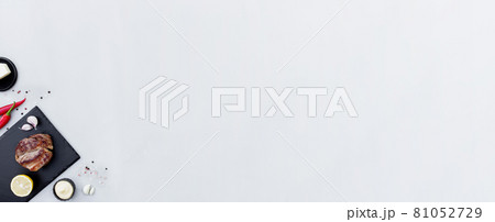 Gray background flat lay with cut of red rib-eye meat on black cutting board Gray background flat lay with cut of red rib-eye meat on black cutting board 81052729
