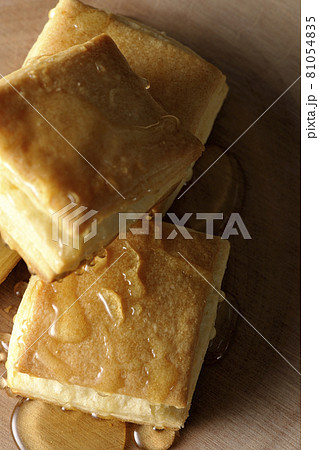 丸太型のカッティングボードの上のホットビスケットにハチミツをかける。 81054835