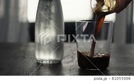 Making espresso tonic in tumbler glass, pour espresso in glass with crushed ice 81055006