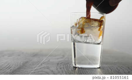 Making espresso tonic in tumbler glass, pour espresso in tonic with ice cube 81055161