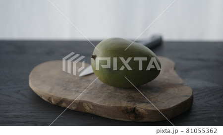 Whole bad mango in halves on olive wood board 81055362