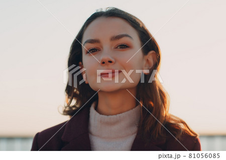 Young smiling brunette woman in coat outdoors portrait Young smiling brunette woman in coat outdoors portrait 81056085