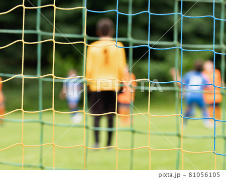 View through soccer gate net. The goalkeeper backs up during the opponents' attack. Abstract view View through soccer gate net. The goalkeeper backs up during the opponents' attack. Abstract view 81056105