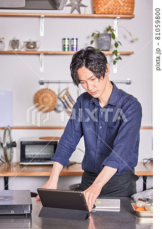 タブレットでレシピを見ながら料理するエプロン姿の若い男性 料理男子イメージ タブレットでレシピを見ながら料理するエプロン姿の若い男性 料理男子イメージ 81059800