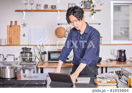 タブレットでレシピを見ながら料理するエプロン姿の若い男性 料理男子イメージ タブレットでレシピを見ながら料理するエプロン姿の若い男性 料理男子イメージ 81059804