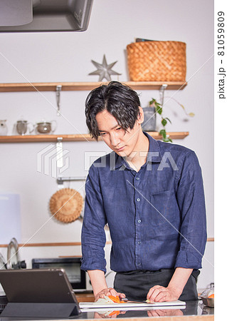 タブレットでレシピを見ながら料理するエプロン姿の若い男性 料理男子イメージ タブレットでレシピを見ながら料理するエプロン姿の若い男性 料理男子イメージ 81059809
