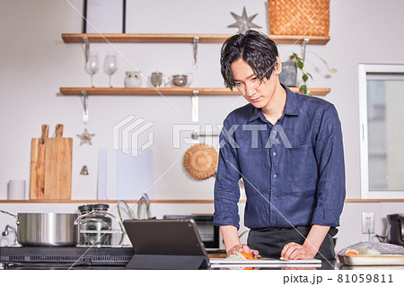 タブレットでレシピを見ながら料理するエプロン姿の若い男性 料理男子イメージ タブレットでレシピを見ながら料理するエプロン姿の若い男性 料理男子イメージ 81059811