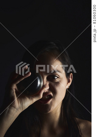 Hispanic teenager playing with a crystal ball on a black background. Mysticism concept 81060300