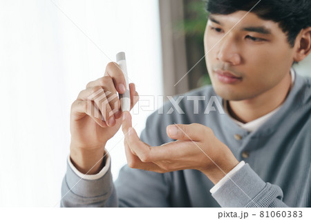 Asian man using lancet on finger for checking blood sugar level by Glucose meter, Healthcare and Medical, diabetes, glycemia concept Asian man using lancet on finger for checking blood sugar level by Glucose meter, Healthcare and Medical, diabetes, glycemia concept 81060383