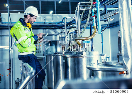 Factory worker engineer working in factory using tablet computer to check maintenance boiler water pipe in factory. 81060905