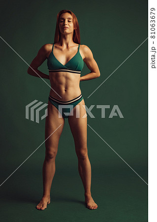 Full length portrait of young beautiful slim tanned red headed woman in lingerie posing isolated over green studio background. Natural beauty concept. Full length portrait of young beautiful slim tanned red headed woman in lingerie posing isolated over green studio background. Natural beauty concept. 81063679