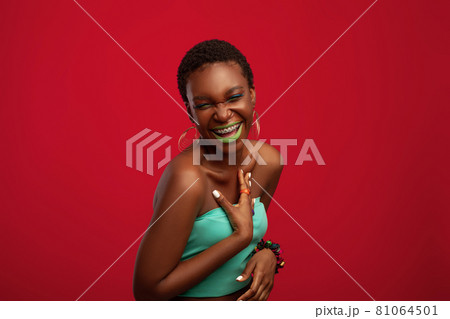 Effective african american young woman laughing on red studio background 81064501