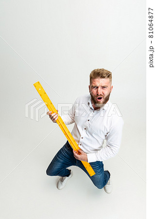 High angle view of funny bearded man, builder, designer or architect with professional equipment isolated on white studio background. High angle view of funny bearded man, builder, designer or architect with professional equipment isolated on white studio background. 81064877