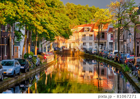 Delt canal with old houses and cars parked along on sunset Delt canal with old houses and cars parked along on sunset 81067271