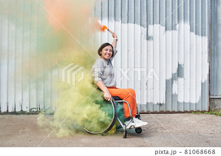 Girl with loss of leg function sitting at wheelchair and playing with bombs with smoke 81068668