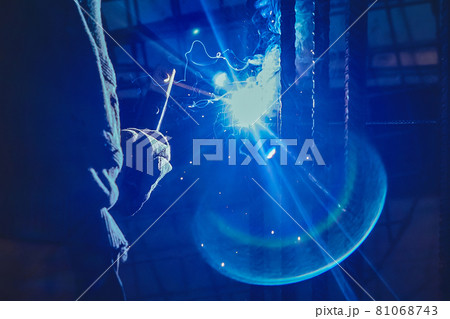 Working man is doing welding work on metal structures in a factory or industrial enterprise 81068743