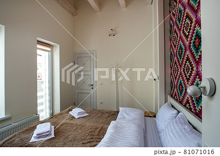Interior of a spacious hotel bedroom with fresh linen on a big double bed. Cozy contemporary room in a modern house. Interior of a spacious hotel bedroom with fresh linen on a big double bed. Cozy contemporary room in a modern house. 81071016