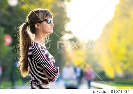 Portrait of young pretty woman standing outdoors on city street in warm autumn day. Portrait of young pretty woman standing outdoors on city street in warm autumn day. 81071454