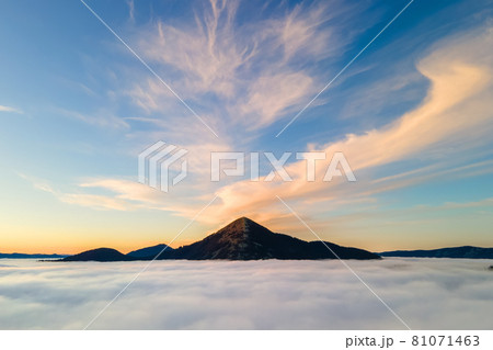 Aerial view of a big mountain over white dense clouds at bright sunrise. Aerial view of a big mountain over white dense clouds at bright sunrise. 81071463