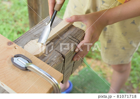 子供が屋外で丸ノミで材木を削っている 81071718