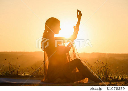 Beautiful female silhouette sit in warm sun Beautiful female silhouette sit in warm sun 81076829