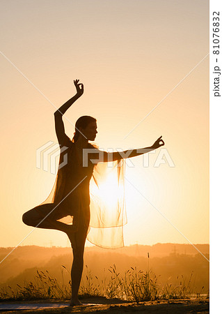Woman stand on one leg against sun Woman stand on one leg against sun 81076832