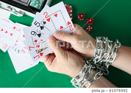Men hands are tied with chain and hold playing cards closeup 81076992
