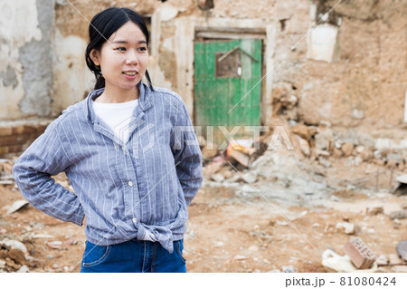 Woman near ruined house 81080424