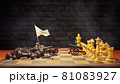 Dark chess raises a white flag in surrender to bright chess on a chessboard and smoke floating in the air and dark brick background. The concept of business loss and bankruptcy. 81083927