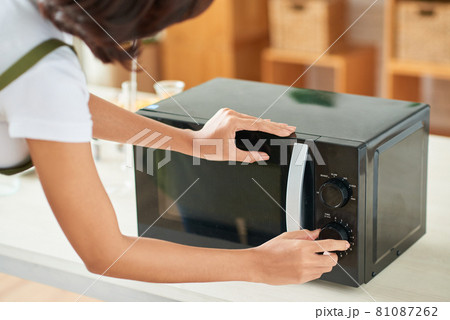 Woman Setting Time on Microwave 81087262