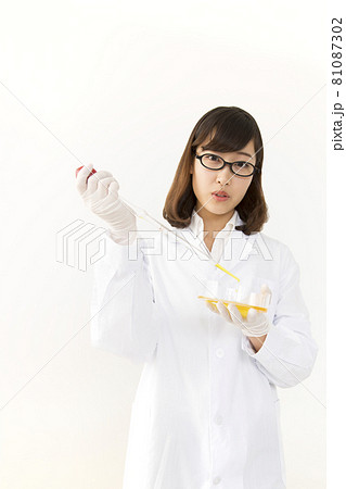 シャーレにピペットで試薬を注ぐ白衣を着た若い女性 81087302