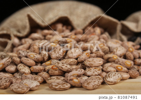 Burlap Bag of Dried Pinto Beans Spilled on Wooden Table Burlap Bag of Dried Pinto Beans Spilled on Wooden Table 81087491