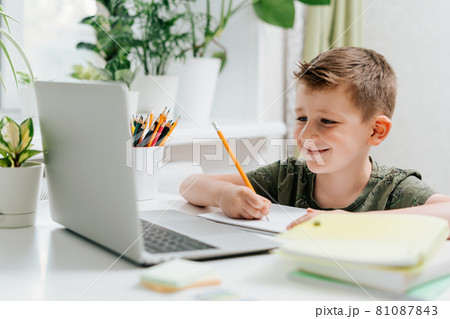 Distance learning online education. Caucasian smile kid boy studying at home with laptop and doing school homework. Thinking child siting with notebook, pencils and training books. Back to school Distance learning online education. Caucasian smile kid boy studying at home with laptop and doing school homework. Thinking child siting with notebook, pencils and training books. Back to school 81087843