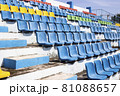 Empty old blue seats in the blue ,yellow green and red in stadium.  81088657