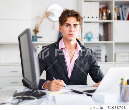 Focused attractive young man working with laptop and documents 81088708