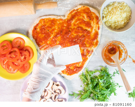 Hand holding empty business card on hear shape pizza dough background Hand holding empty business card on hear shape pizza dough background 81091160