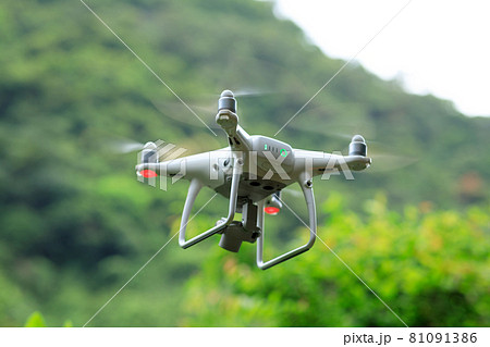 White drone with camera flying in summer mountains White drone with camera flying in summer mountains 81091386