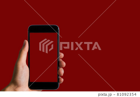 Female holding a black smartphone with a touch screen in Red background. Female holding a black smartphone with a touch screen in Red background. 81092354