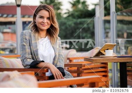 Charming young business lady sitting at the table outdoors Charming young business lady sitting at the table outdoors 81092676