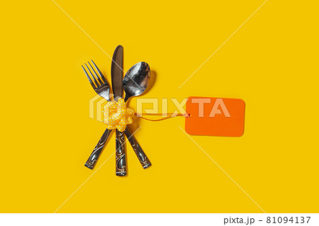 Vintage silverware with an empty tag on bright yellow background Vintage silverware with an empty tag on bright yellow background 81094137
